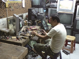 フィリピンで日本から輸入された中古ブラウン管テレビを修理・調整している様子の写真